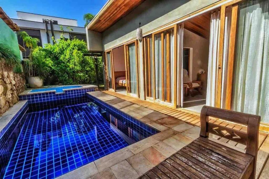 a swimming pool with a bench next to a house at Camburi Beach House - Casa térrea a 50 m da praia in São Sebastião