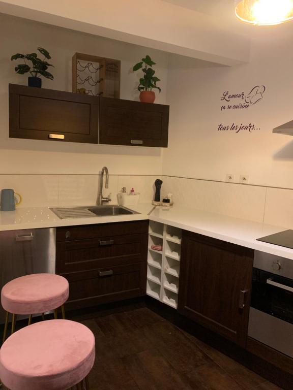 een keuken met een wastafel en twee roze krukken bij Appartement Cosy et chaleureux in Montreuil