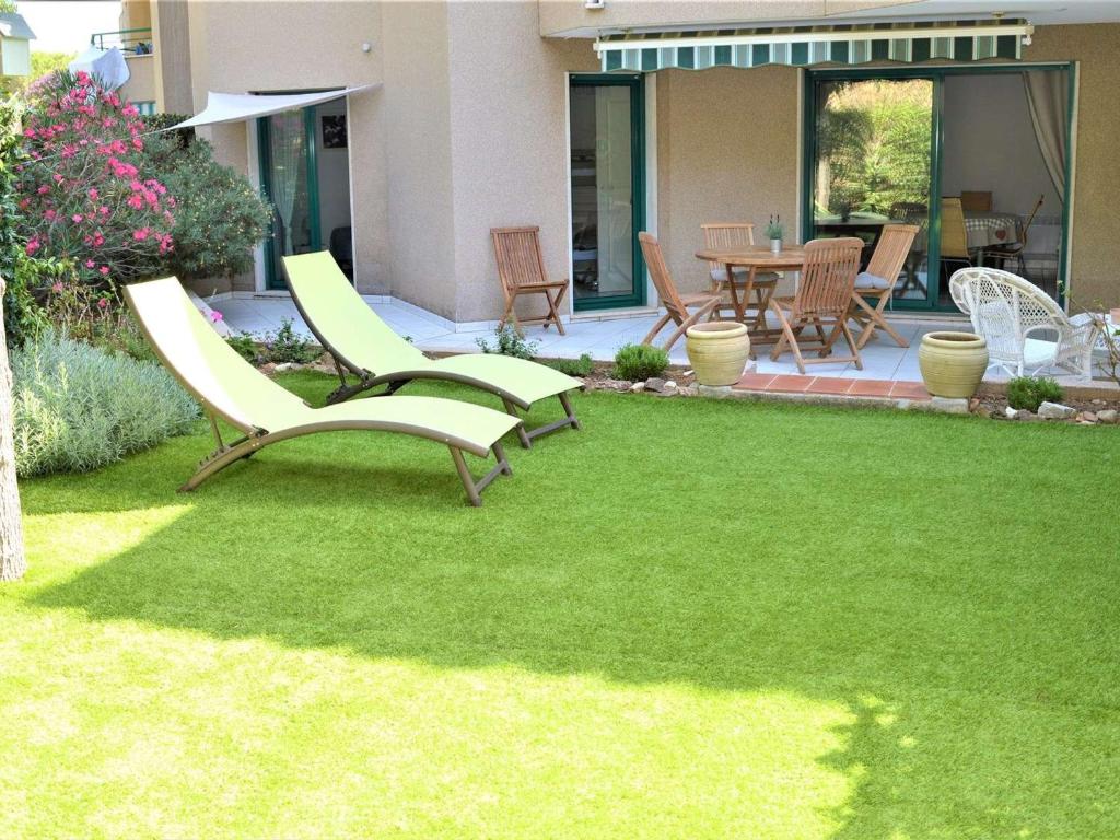 a lawn with two chairs and a table and chairs at Appartement Cavalaire-sur-Mer, 3 pièces, 6 personnes - FR-1-226B-32 in Cavalaire-sur-Mer