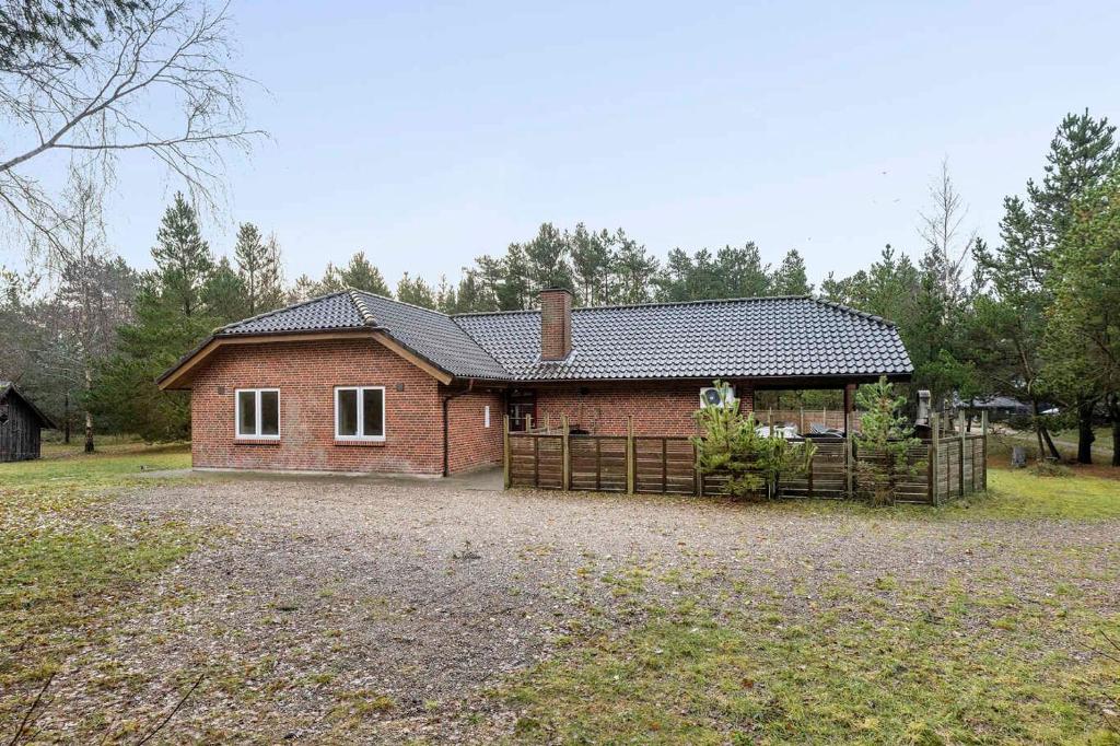 a red brick house with a fence in a field at Large Cottage In Peaceful, Beautiful Nature in Mølby