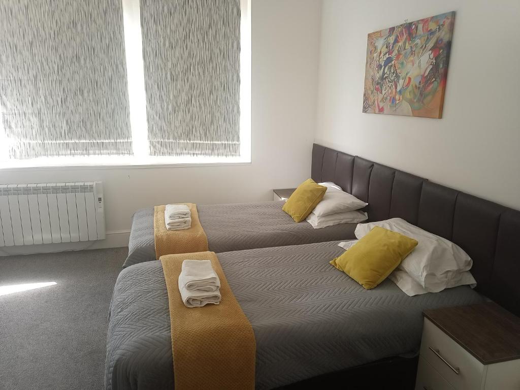 2 camas en una habitación con almohadas amarillas en Hull City Centre Accommodation 2, en Hull