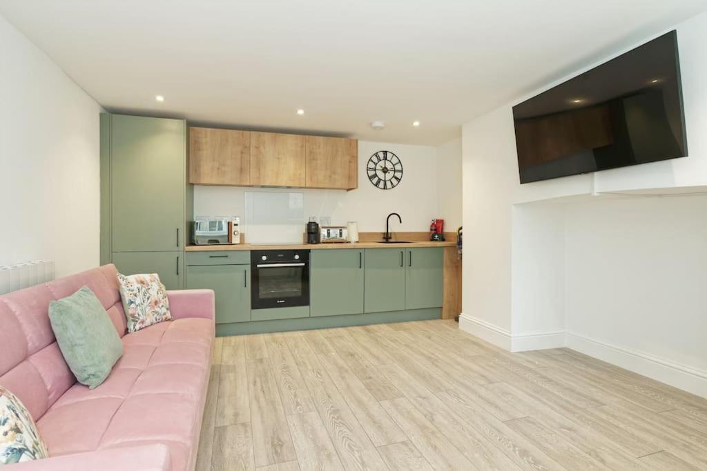 sala de estar con sofá rosa y cocina en Stylish Beach Front Retreat en Kent