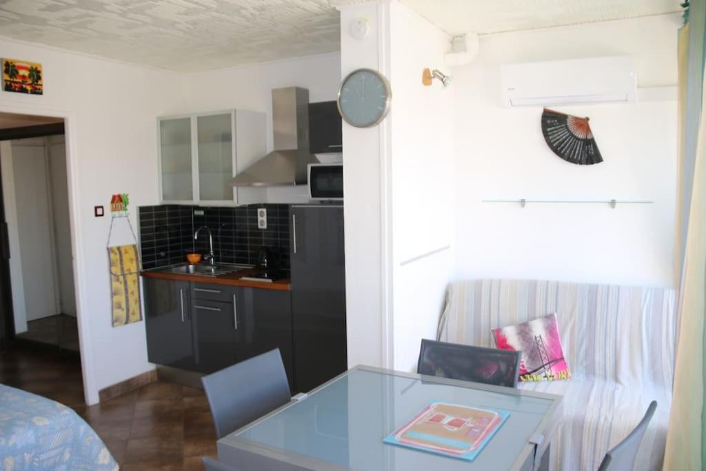 ein Wohnzimmer mit einem Tisch und einer Küche in der Unterkunft Studio 34, Héliopolis E au village naturiste in Cap d'Agde