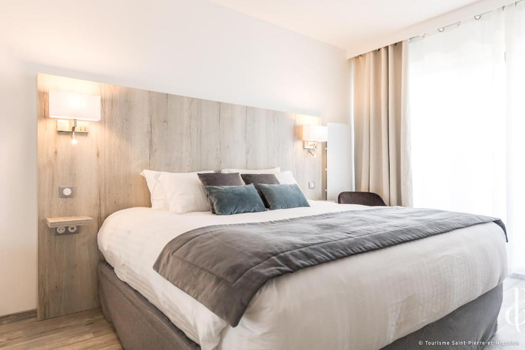 Les Terrasses du Port في سانت-بيير: غرفة نوم مع سرير كبير مع وسادتين زرقاوين
