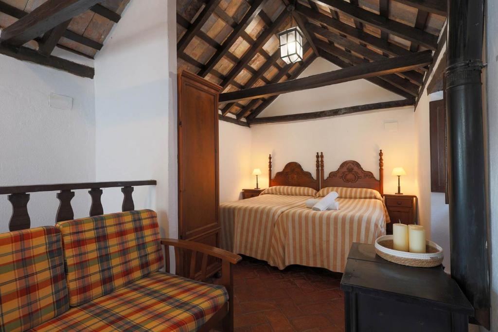 a bedroom with two beds and a chair at Casas Rurales Tugasa Castillo de Castellar in Castellar de la Frontera