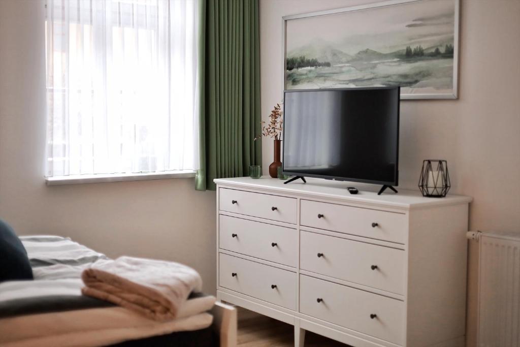 a bedroom with a white dresser with a tv on it at Pößnecker Werkstätten - FeWo Katharina von Bora in Pößneck