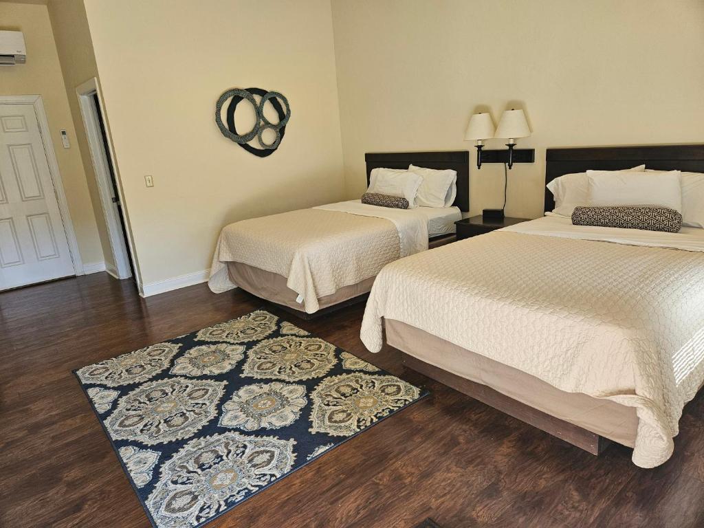 a bedroom with two beds and a rug at Sunset Cottage Motel Rooms in Ligonier