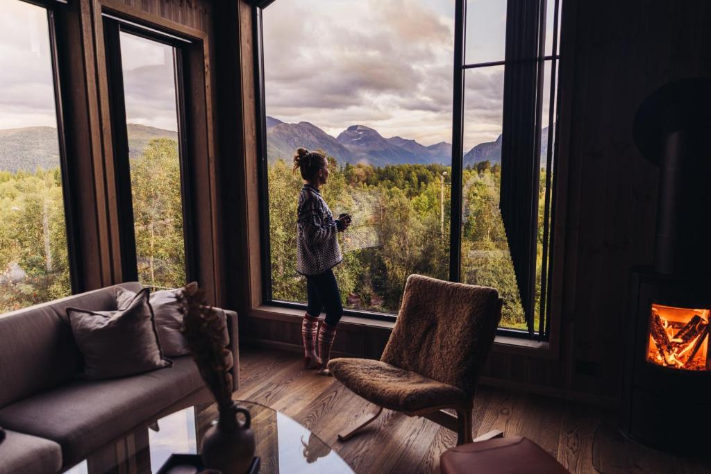 a girl standing in a room looking out of a window at Premium Mountain Penthouse with Sauna, Strandafjellet - 602 in Stranda