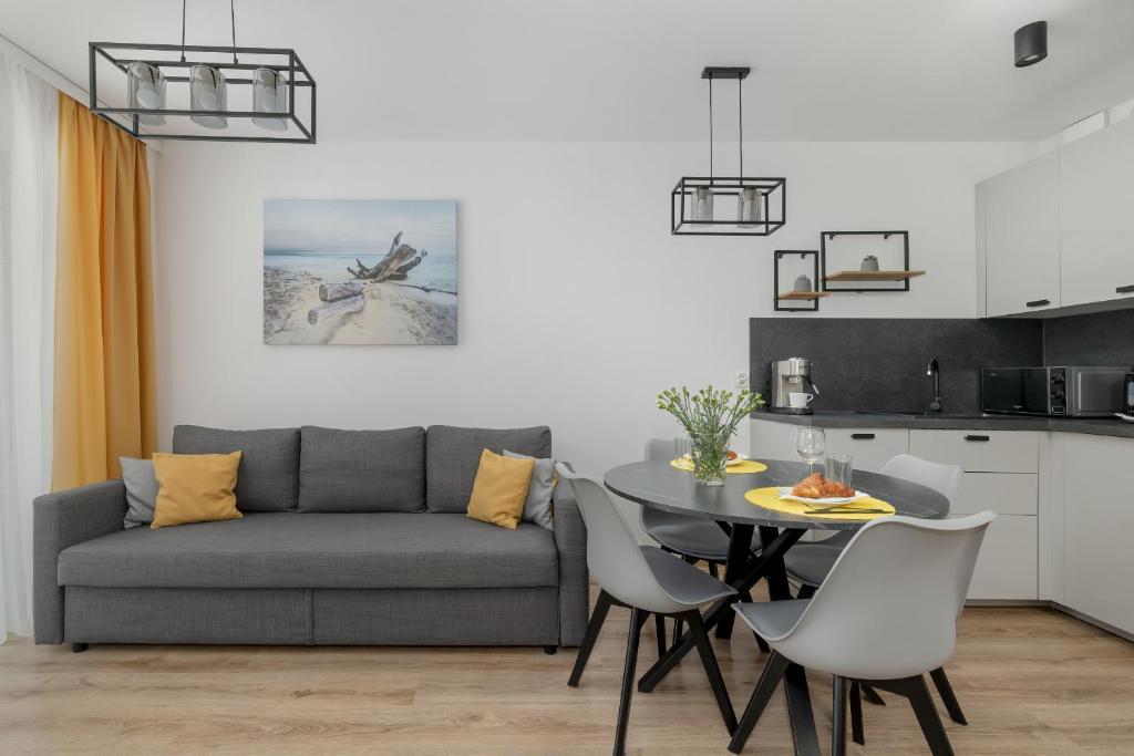 a living room with a table and a couch at Exclusive and Modern Grey Apartment with Furnished Balcony in Kołobrzeg by Noclegi Renters in Kołobrzeg