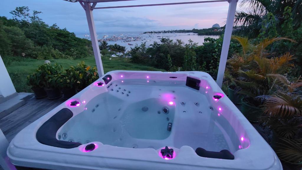 a bath tub on a porch with a view of the water at Jacuzzi, Sauna, Piscine et Magnifique Vue sur la Mer ! Vivez le Luxe de la Dépendance de la Villa Nadia in Le Diamant