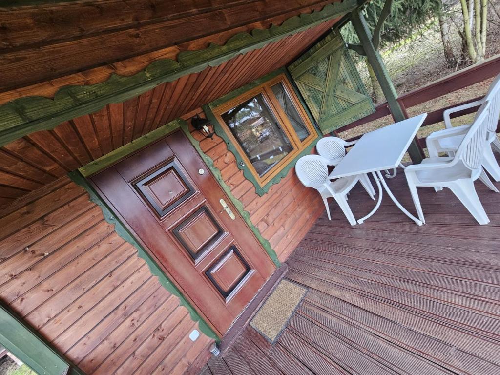 einen Blick über eine Holzterrasse mit einem Tisch und Stühlen in der Unterkunft Agro Rancho domki in Podgórzyn