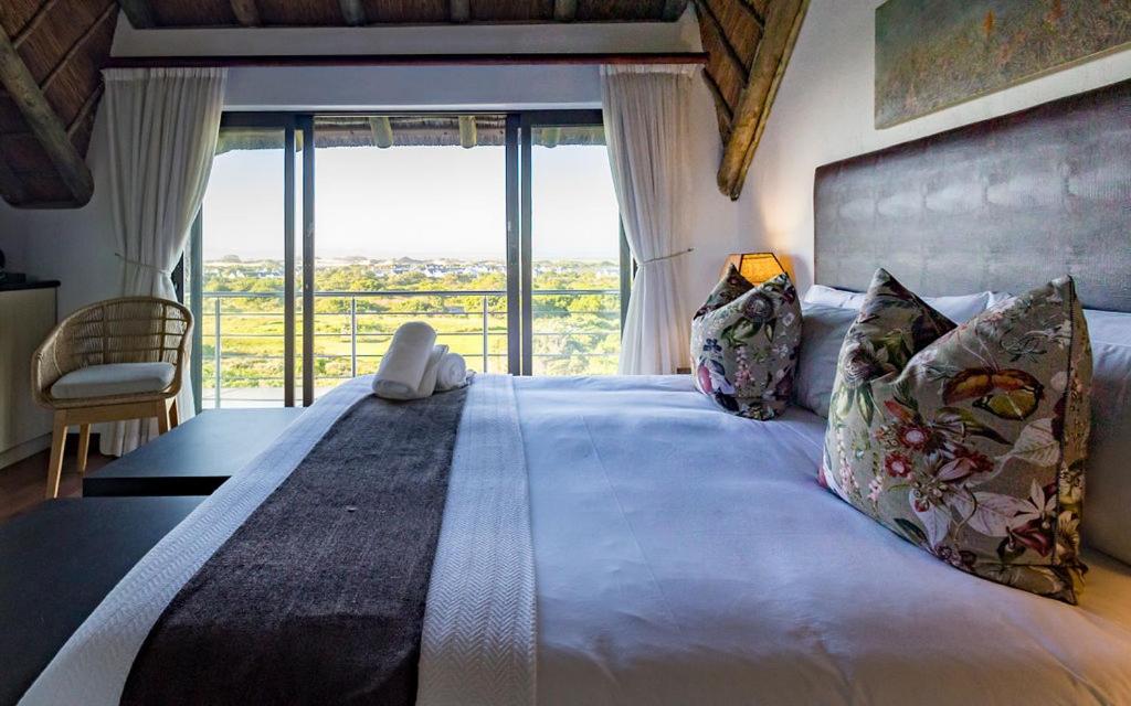 1 dormitorio con 1 cama grande y ventana grande en St Francis Golf Lodge, en St Francis Bay