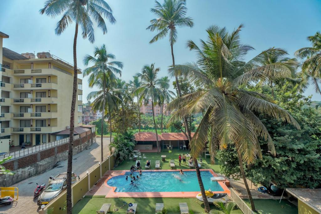- une vue sur la piscine d'un complexe avec des palmiers dans l'établissement Rosa Bella Resort-TBV, à Calangute