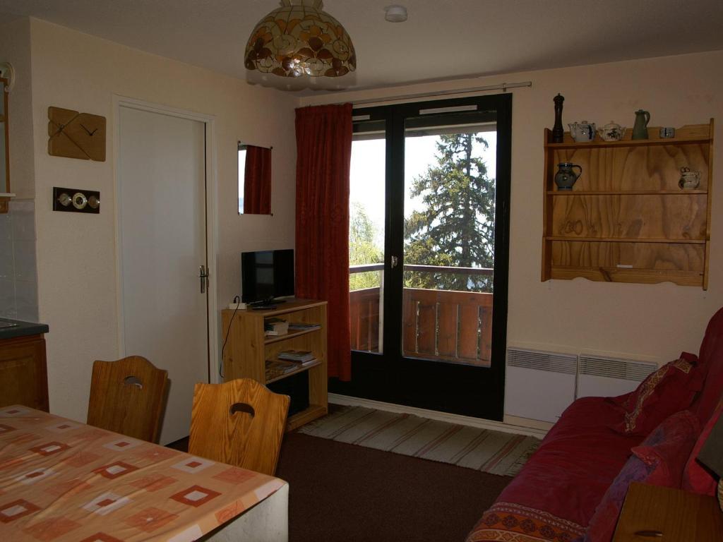 un salon avec une table et une grande fenêtre dans l'établissement 2 pièces cabine au pied des pistes avec balcon, cuisine équipée et services optionnels - FR-1-557-64, à Les Adrets