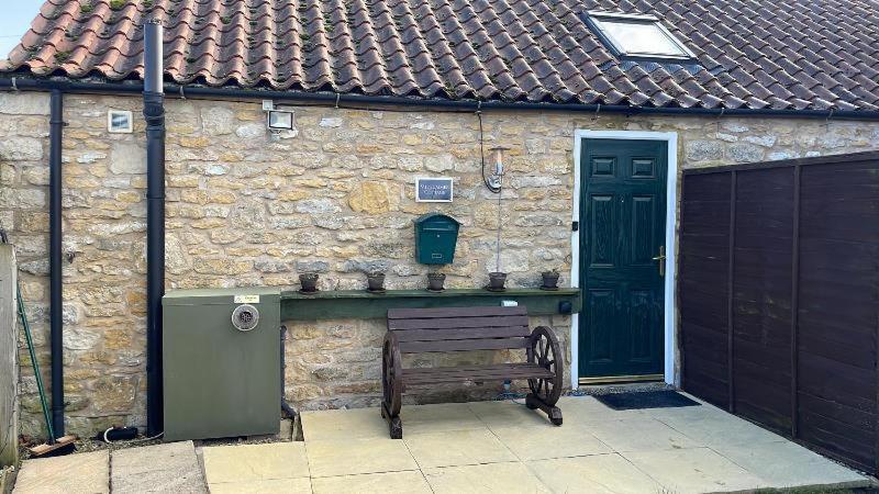 a stone building with a gate and a wooden bench at midsummer cottage in Kirby Misperton