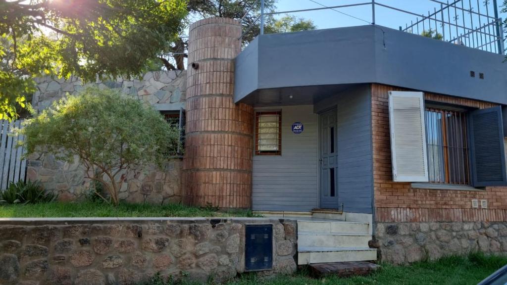 ein Backsteinhaus mit einer Steinmauer davor in der Unterkunft Altos de Capilla in Capilla del Monte
