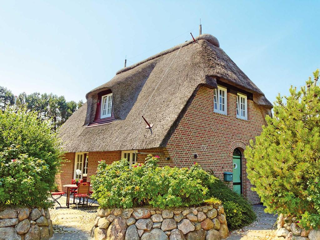 a large brick house with a thatched roof at Enenhoog Flugente von Appartements & Mehr in Kampen