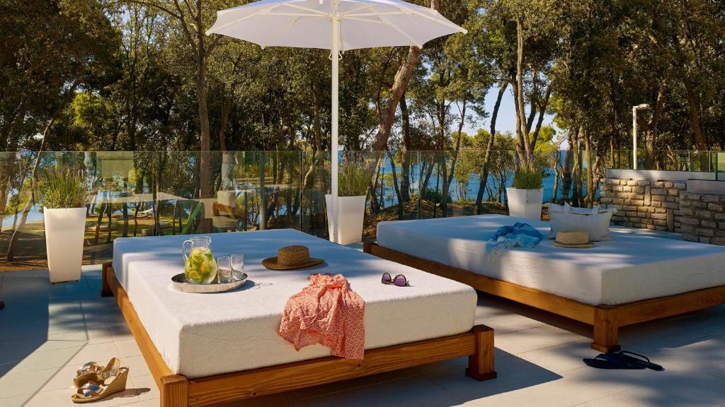 two beds sitting on a patio with an umbrella at Park Plaza Arena Pula in Pula