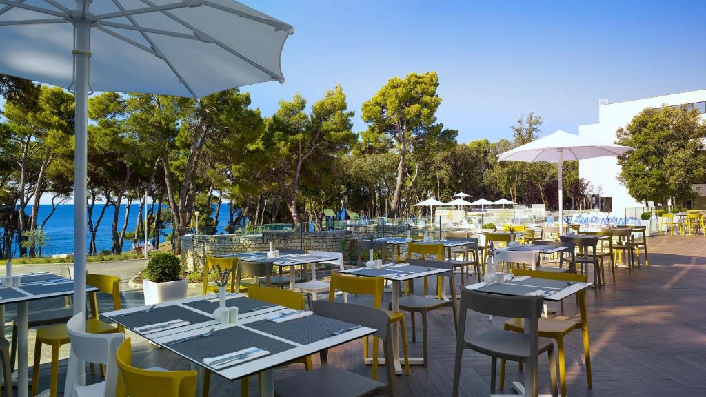 a restaurant with tables and chairs and an umbrella at Park Plaza Arena Pula in Pula