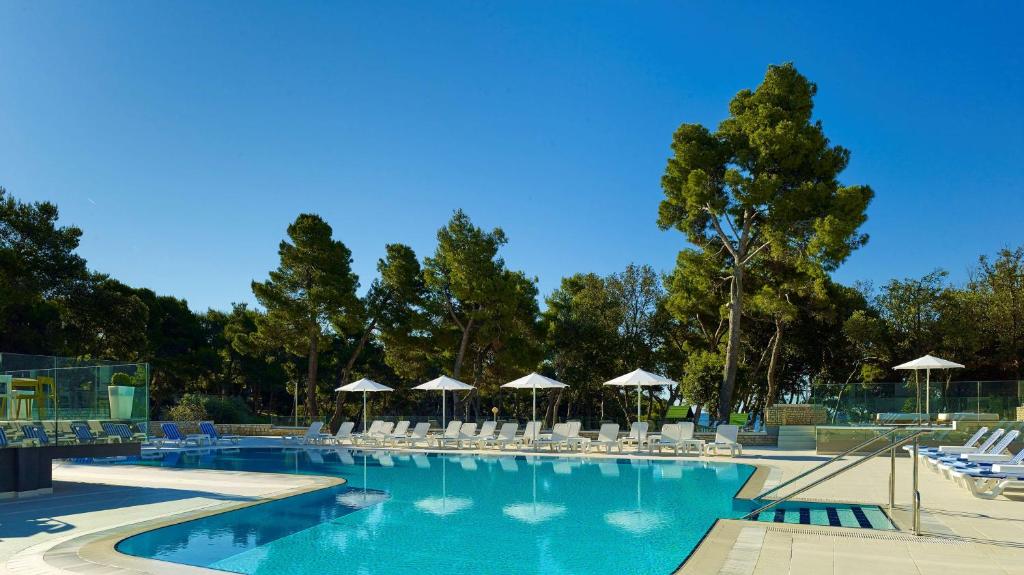 a large swimming pool with chairs and umbrellas at Park Plaza Arena Pula in Pula