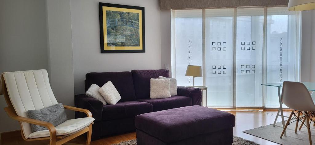 a living room with a purple couch and a chair at Apartamento en Coruña con parking in A Coruña