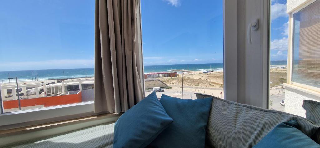 a window with a view of the ocean and a train at The Sun - by Caparica Villas in Costa da Caparica