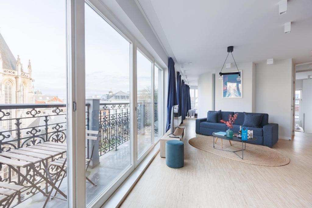 un soggiorno con divano blu e balcone di Sweet Inn - Regence a Bruxelles