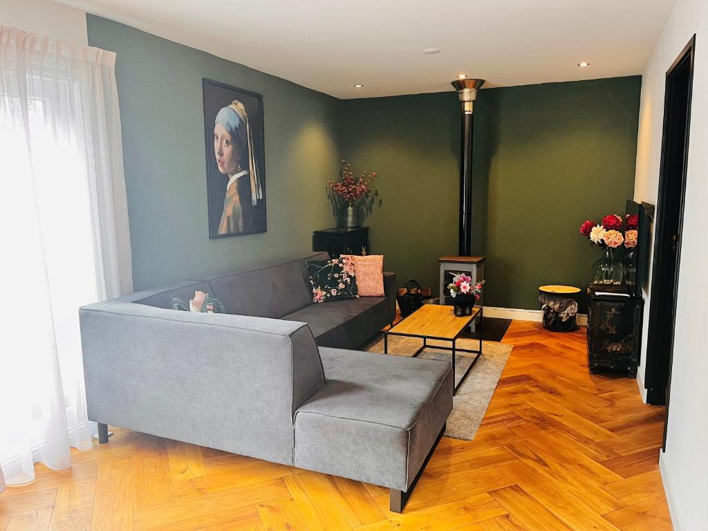 a living room with a gray couch and a painting at Casa Clementine - Boutique Guesthouse in Veldhoven