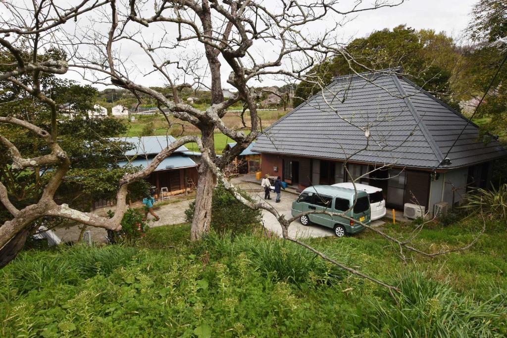 una casa con una furgoneta verde aparcada frente a ella en 佐左衛門（さざえもん） en Yokosuka