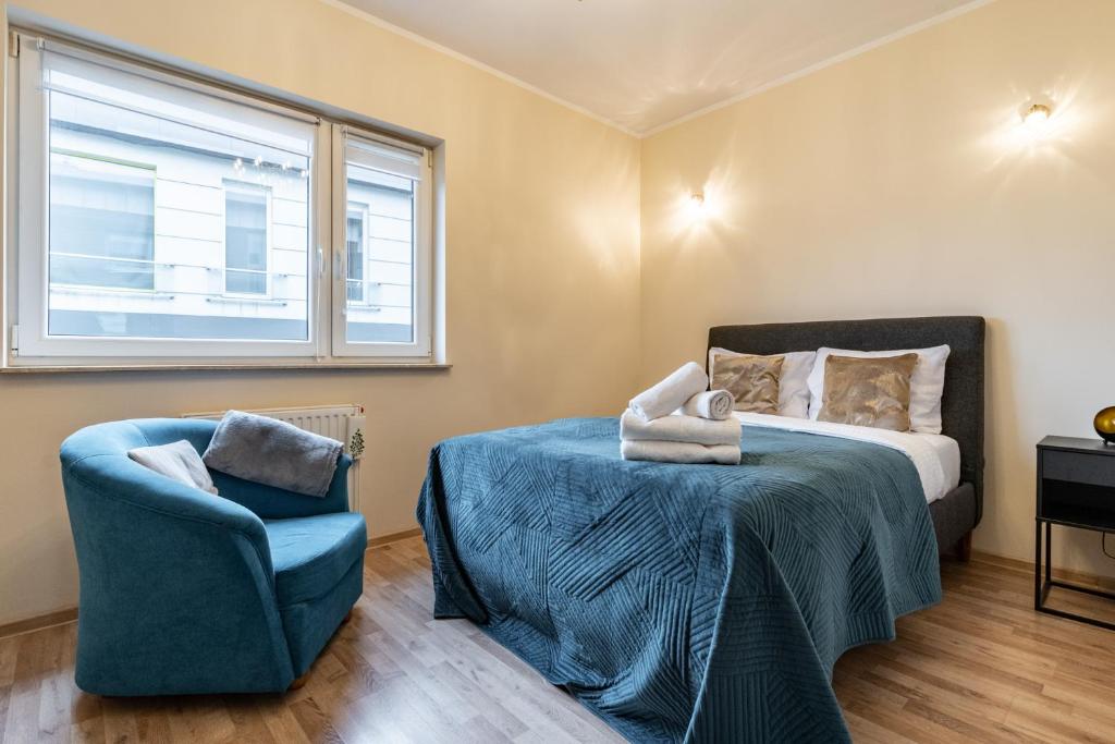 a bedroom with a bed and a chair and a window at Orkana Comfort Apartment in Katowice