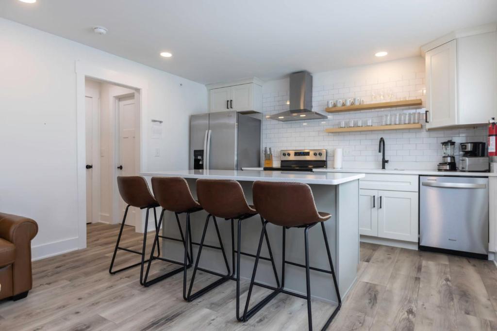 Una cocina con gabinetes blancos y taburetes de bar. en Ocean Lofts in the Vibe #6 - 5 min walk to beach, en Virginia Beach