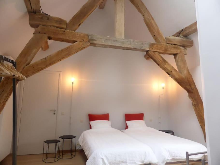 two beds in a room with wooden beams at Ferme de la Porte Rouge in Andenne