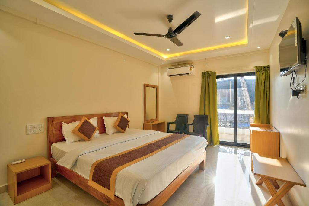 a bedroom with a bed and a large window at Baga Beach Walk in Baga