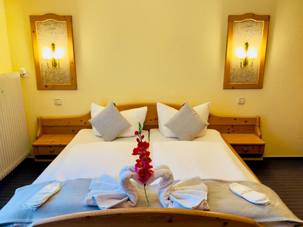 ein Schlafzimmer mit 2 Betten mit Handtüchern und einer Blume darauf in der Unterkunft Hotel Restaurant Adler Stube in Münstertal