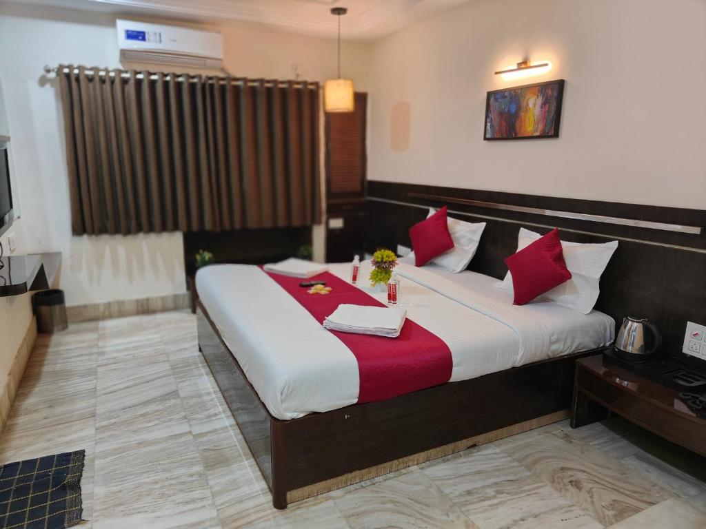 a bedroom with a large bed with red pillows at HOTEL SHIRDI INN in Shirdi