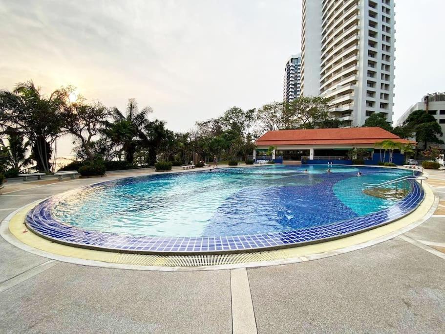 a large swimming pool in a parking lot with a building at Moderne og delikat leilighet på stranden i Jomtien in Pattaya South