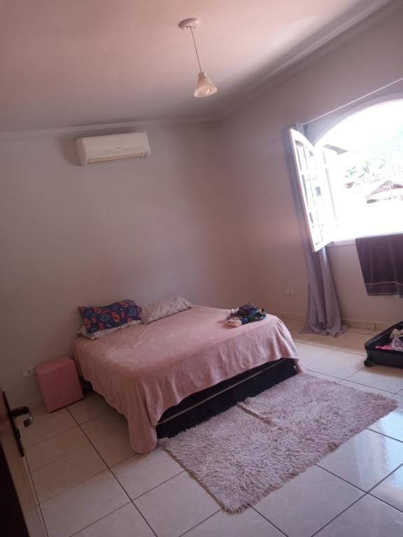 a bedroom with a bed in a room with a window at Suite região central in Ubatuba