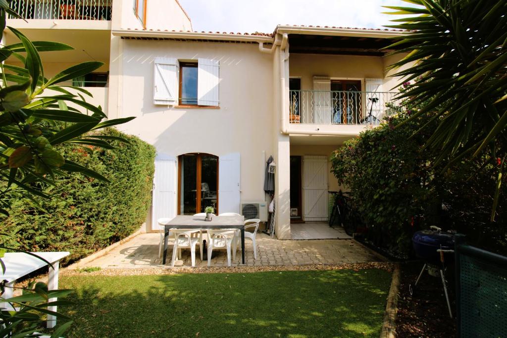 a table and chairs in front of a house at CARBAU Maisonnette pour 8 personnes dans une résidence privée avec piscine à Carqueiranne in Carqueiranne
