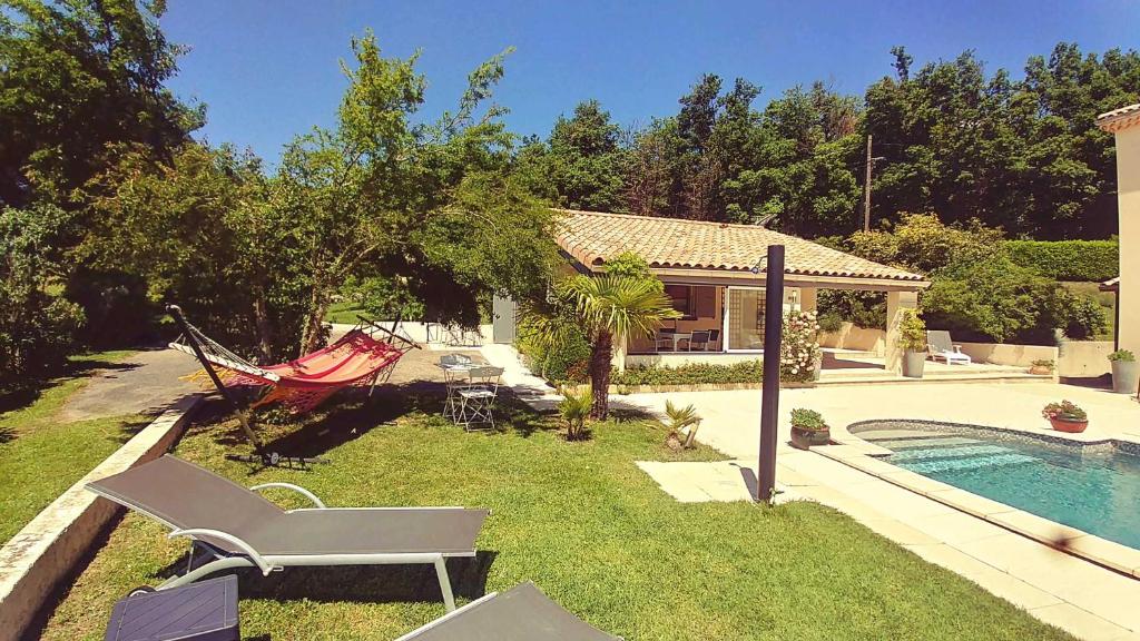een tuin met een hangmat en een huis met een zwembad bij Le Prieuré in La Motte-de-Galaure