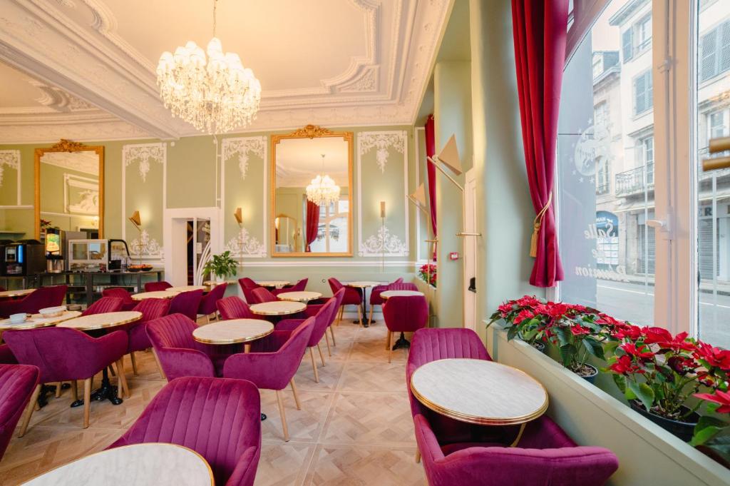 een restaurant met paarse stoelen en tafels en een kroonluchter bij Grand Hôtel de l'Europe in Morlaix