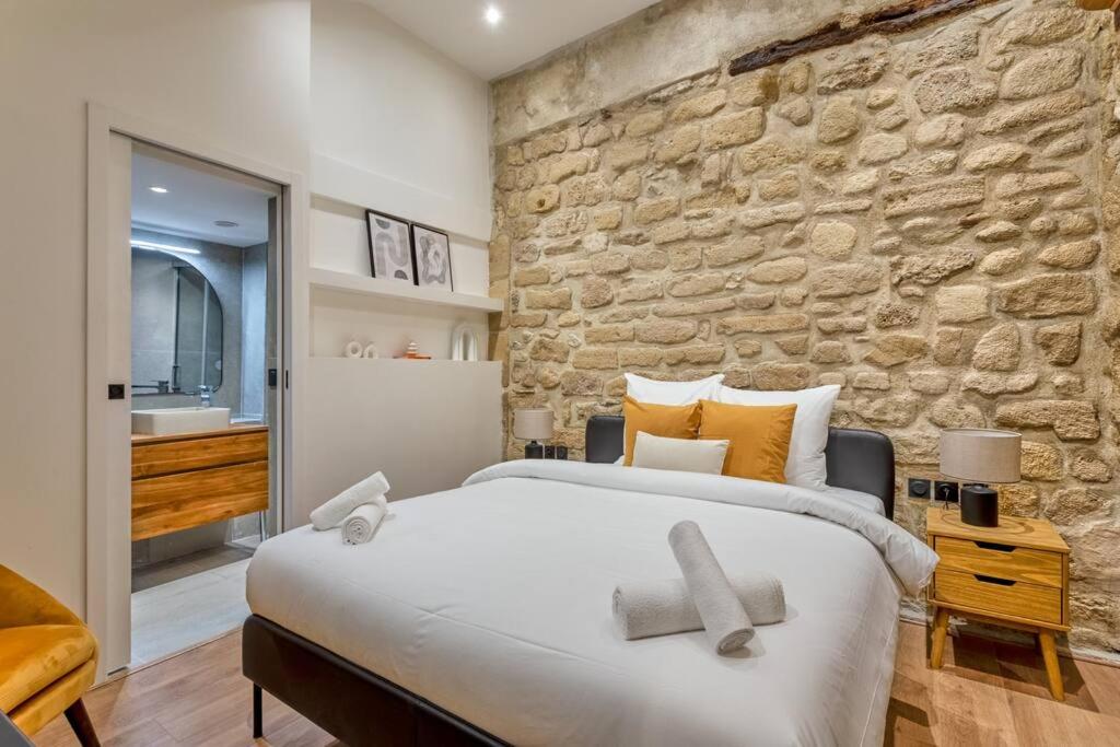une chambre avec un grand lit et un mur en pierre dans l'établissement Typical Parisian Apartment in Le Marais#4 pers, à Paris