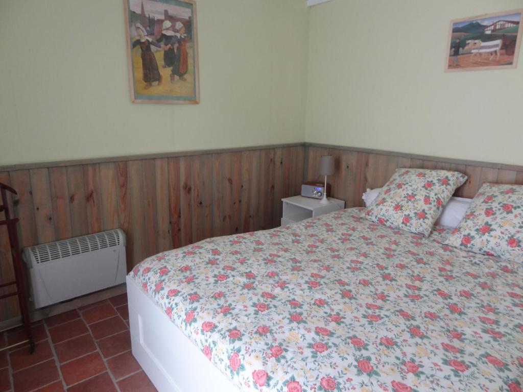 1 dormitorio con 1 cama con colcha de flores en Les Ecuries du Préchard, en La Chapelle-Chaussée