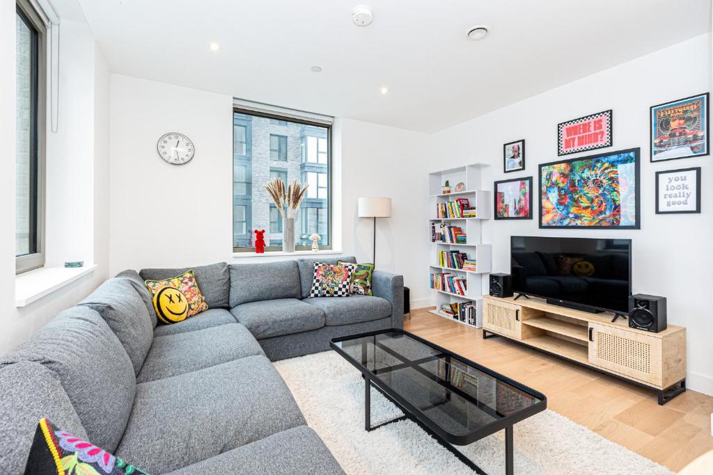 a living room with a gray couch and a tv at Modern New 1BR wbalcony, 2min Tottenham Hale Tube in London