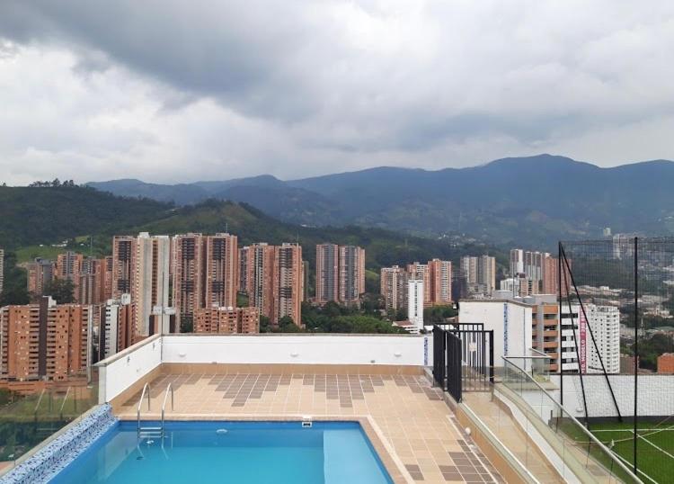 een zwembad bovenop een gebouw met een stad bij Impecable y lujoso apartamento para una estadía unica in Medellín