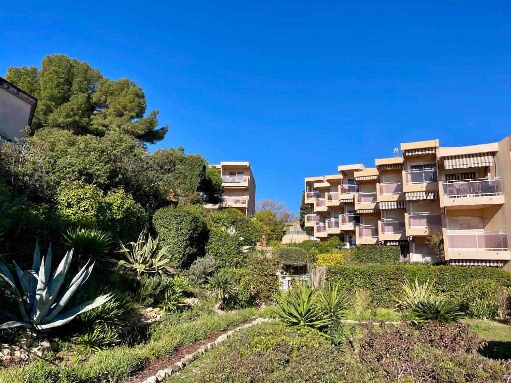un immeuble d'appartements avec des arbres et des plantes sur une colline dans l'établissement Tout proche de la plage, à 12 min à pied du port, place de parking, à Bandol