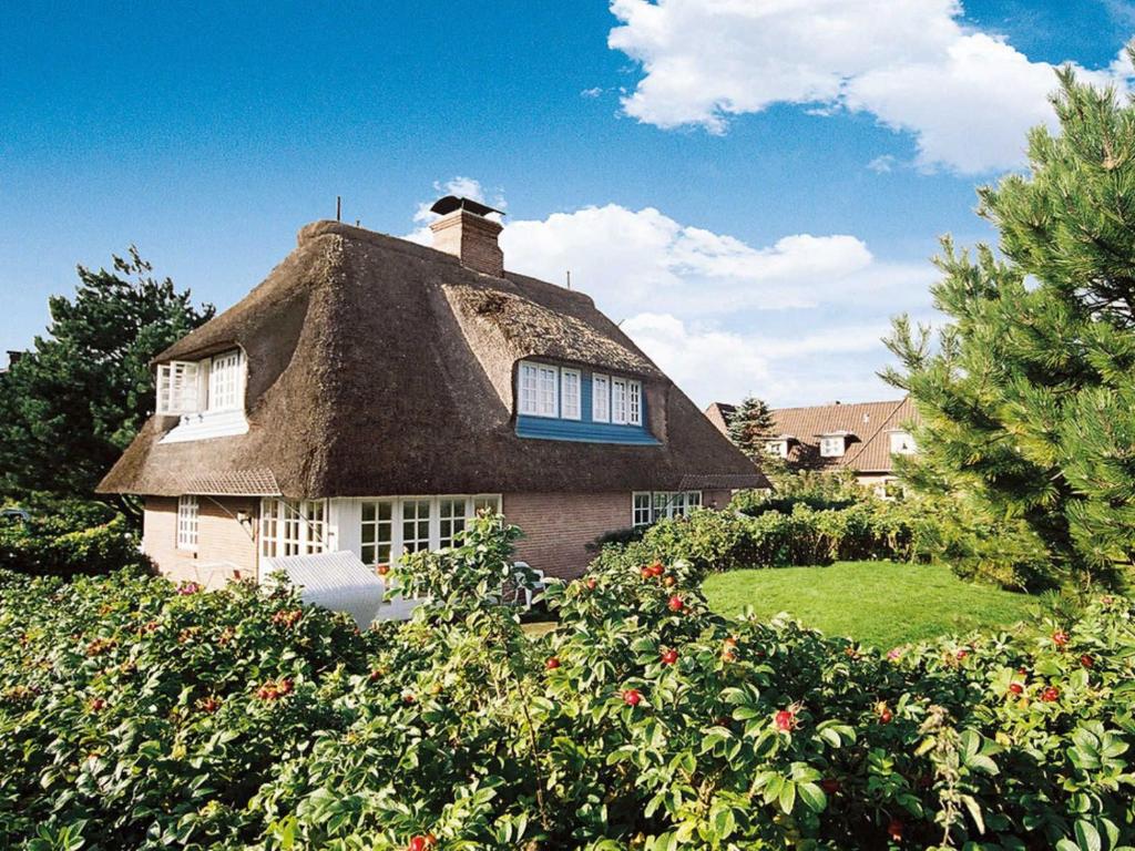 a thatched house with a thatched roof in a garden at Käpt'n Cook 4 von Appartements & Mehr in Kampen