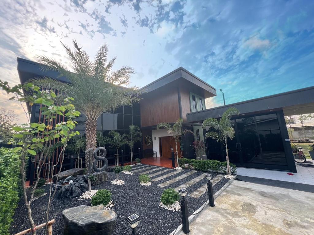 a house with a palm tree in front of it at โค้งโดนัท พรีเมียม พูลวิลล่า in U Thong