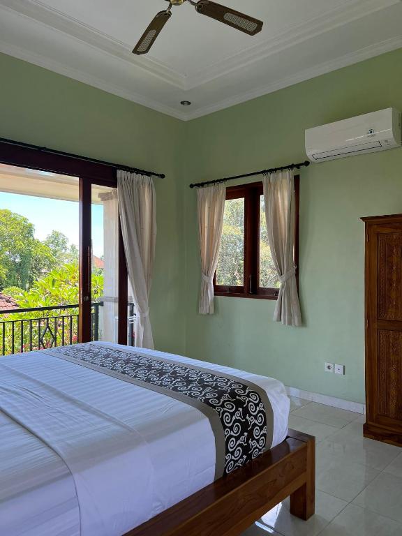 a bedroom with a bed and a balcony with windows at Sudiana House in Ubud