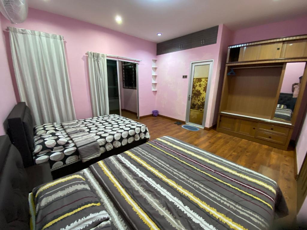 a bedroom with pink walls and a bed and a dresser at Frosty Hills Homestay in Tanah Rata