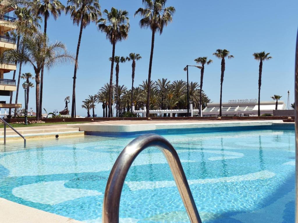 ein Pool mit Palmen im Hintergrund in der Unterkunft Luminoso apartamento de 3 dormitorios a pie de playa en Torremolinos in Torremolinos